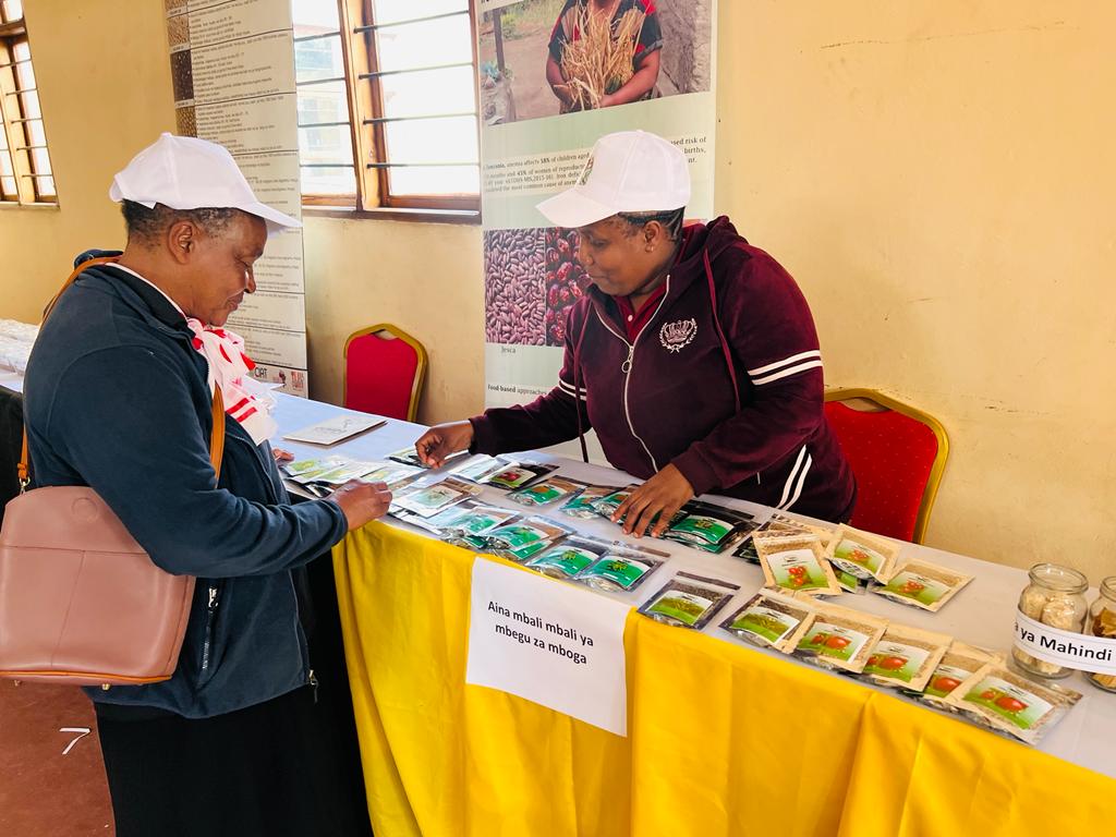 Miss Hellen Msuya, Researcher from TARI Tengeru is explaining to a stakeholder about vegetable production on Nane nane exhibition at Themi ground Arusha. 