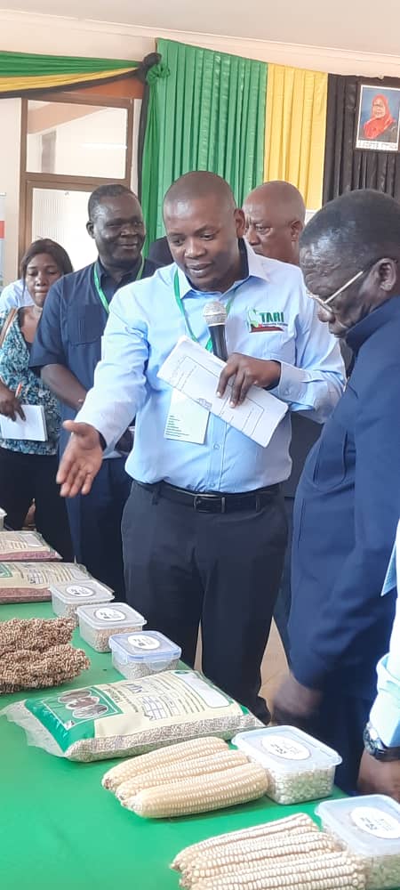 DR. Emmanuel Chilagane giving briefing to Former Prime Minister of the United Republic of Tanzania (in a blue suit) Hon. Mizengo Pinda on some of available technologies at Tanzania Agricultural Research Institute (TARI) - Ilonga Centre during Farmers Agri
